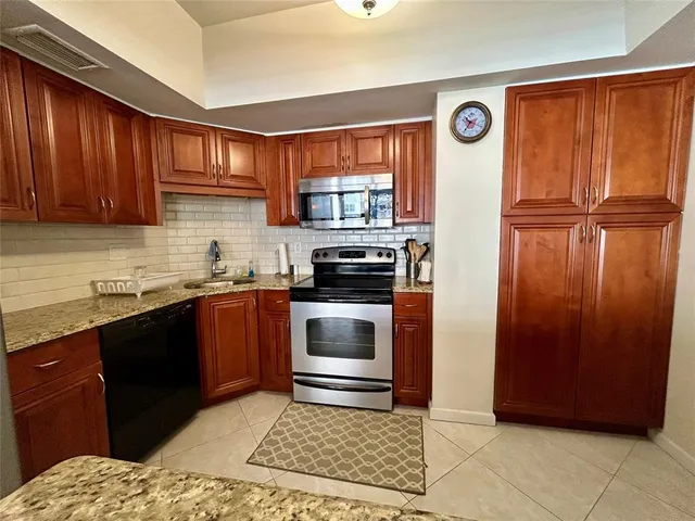 a kitchen with granite countertop wooden cabinets and stainless steel appliances
