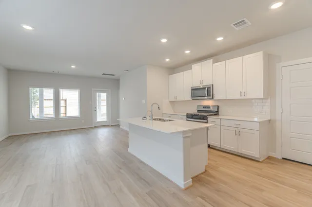 a kitchen with white cabinets stove and sink