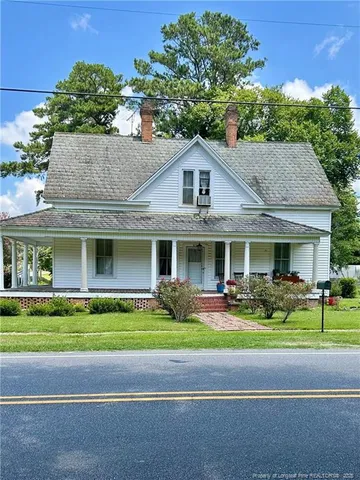 a front view of a house with a garden and trees