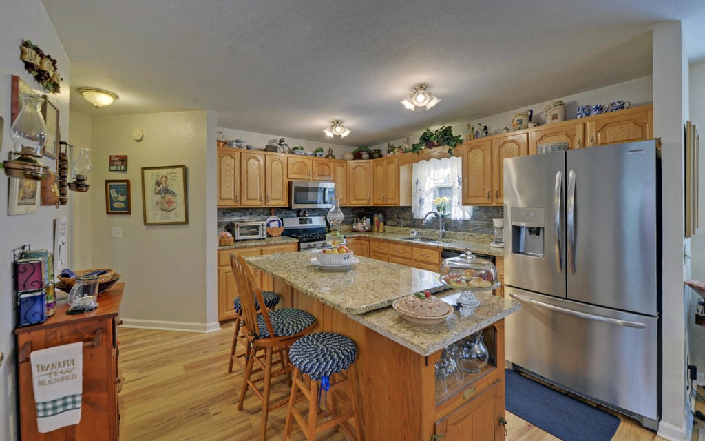7300 Mr Bert Road Hiawassee, GA 30546 - Photo 13 of 48 a kitchen with stainless steel appliances granite countertop a refrigerator a stove a sink a dining table and chairs with wooden floor