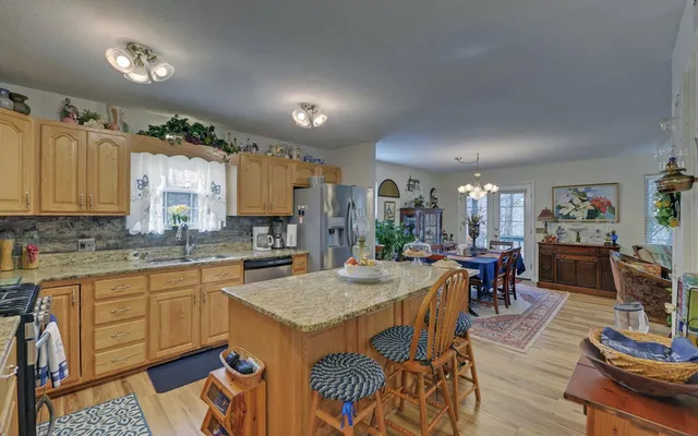 a kitchen with stainless steel appliances granite countertop a stove a sink dishwasher a dining table and chairs with wooden floor