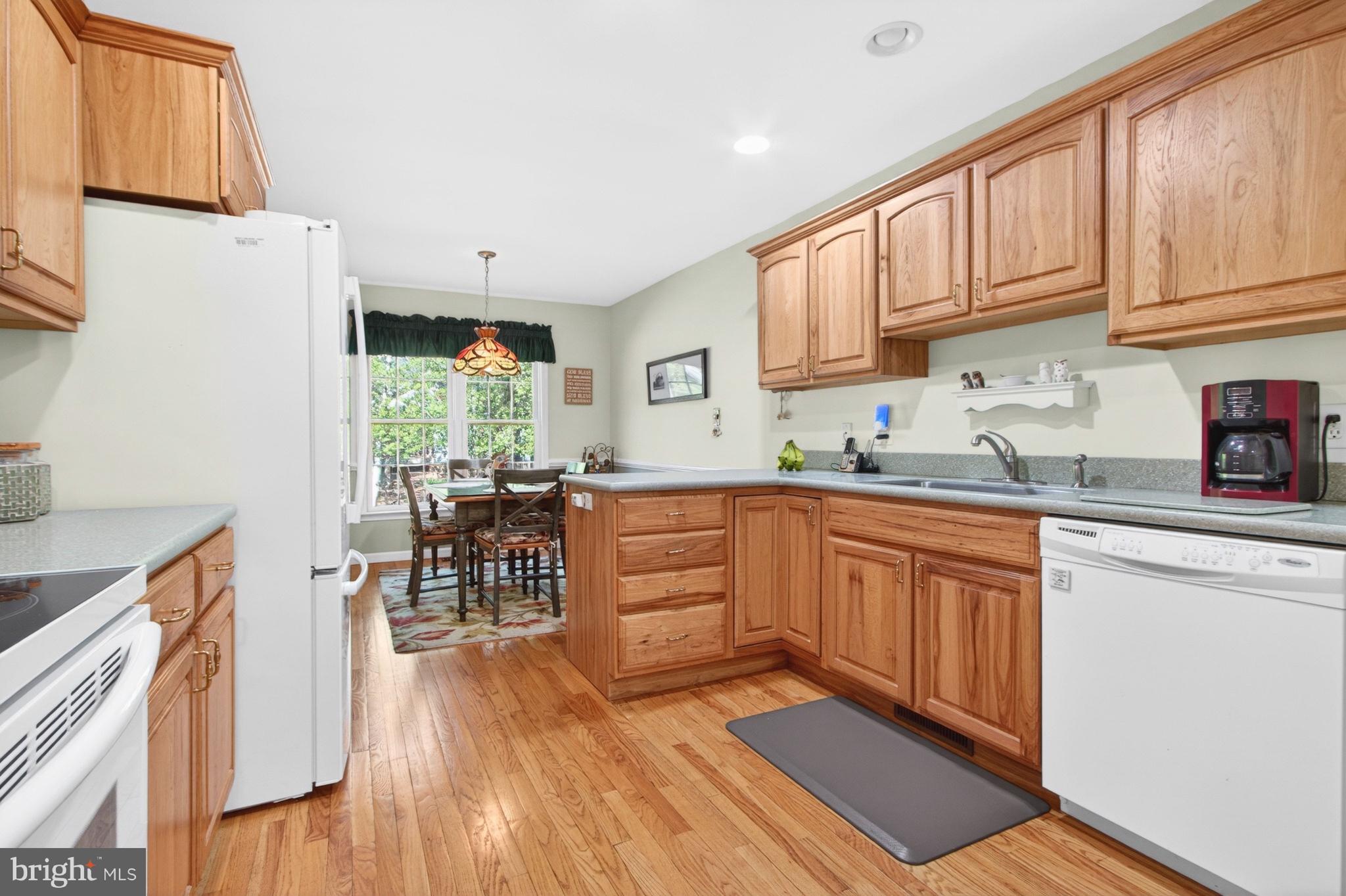 34371 Owls Nest Road Lewes, DE 19958 - Photo 9 of 58 a kitchen with stainless steel appliances granite countertop a refrigerator a sink dishwasher a stove and white countertops with wooden floor