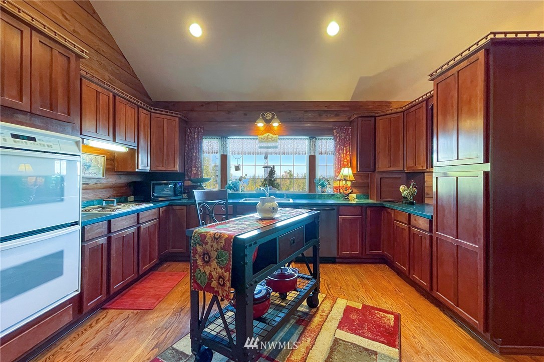 1006 Happy Valley Road Sequim, WA 98382 - Photo 16 of 40 a kitchen with stainless steel appliances granite countertop a refrigerator a stove and a wooden floors