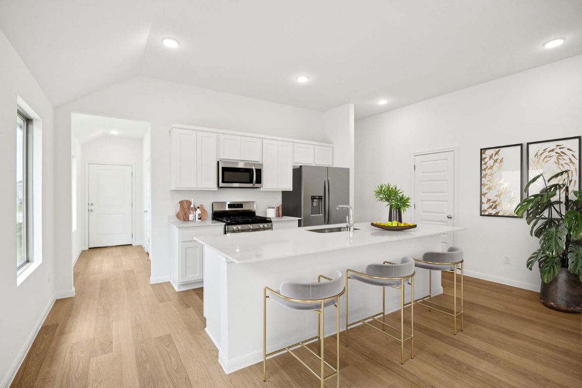 435 Lucky Avenue Elgin, TX 78621 - Photo 2 of 36 a kitchen with stainless steel appliances a stove top oven a refrigerator a sink a dining table and chairs with wooden floor