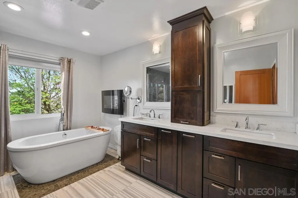 15465 Eastvale Road Poway, CA 92064 - Photo 34 of 44 a bathroom with a double vanity sink a large mirror and a bathtub