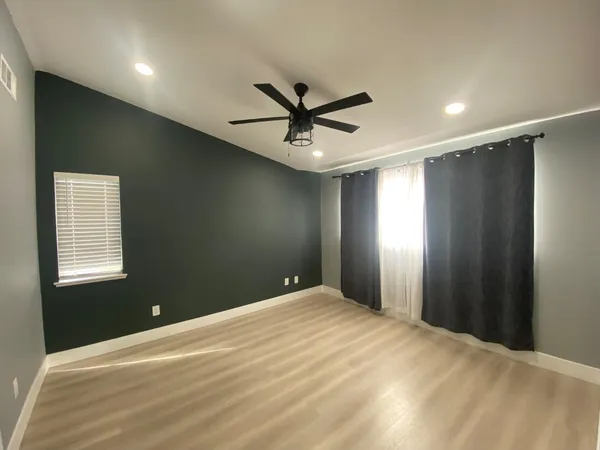 a view of an empty room with window and wooden floor