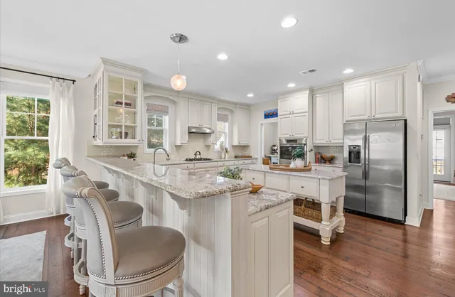 a large kitchen with stainless steel appliances kitchen island granite countertop a lot of counter space and wooden floors
