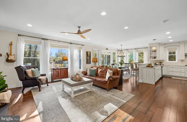 a living room with furniture kitchen view and a wooden floor