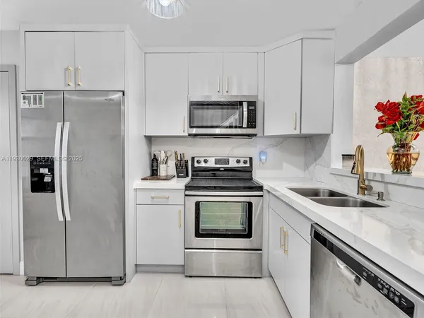 a kitchen with stainless steel appliances granite countertop white cabinets a refrigerator and a sink