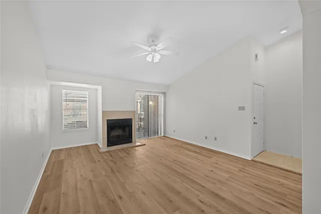 a view of empty room with fireplace and wooden floor