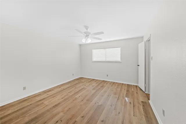 an empty room with a window and a ceiling fan