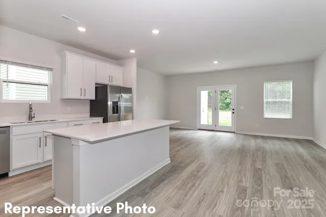 a kitchen with stainless steel appliances a sink a stove a refrigerator cabinets and a window