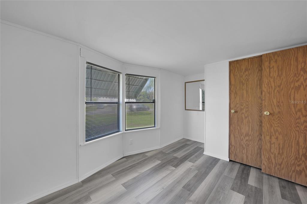1298 Southeast Lake Road Arcadia, FL 34266 - Photo 11 of 35 an empty room with wooden floor and windows