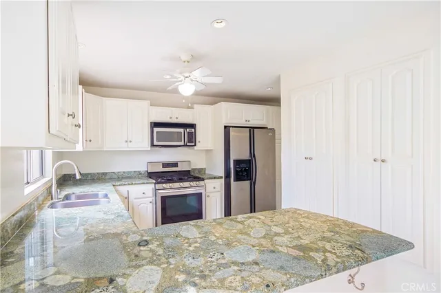 a kitchen with granite countertop a refrigerator stove and microwave