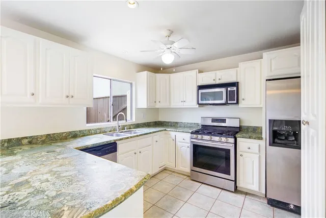 a kitchen with kitchen island white cabinets appliances and a chandelier