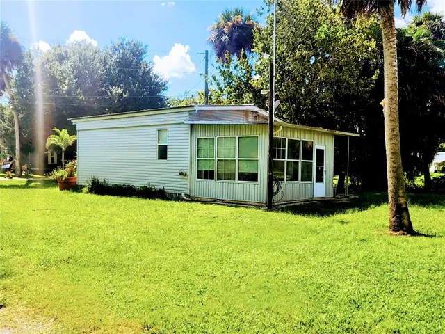 a view of a white house with a big yard and potted plants