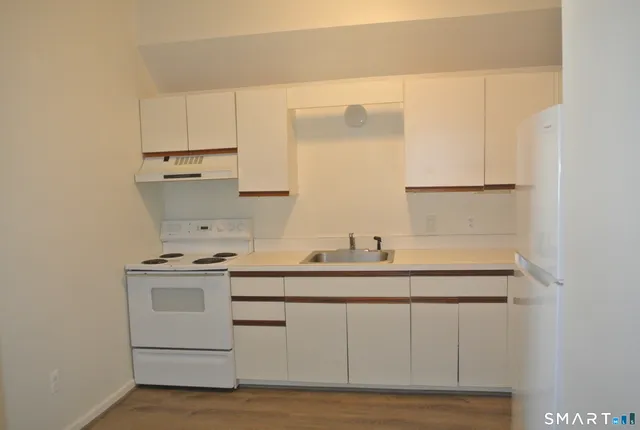 a kitchen with white cabinets sink and stove