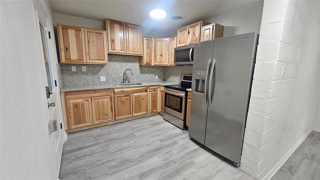 1015 South Welch Street, Unit A Denton, TX 76201 - Photo 14 of 21 a kitchen with stainless steel appliances granite countertop a refrigerator sink and cabinets