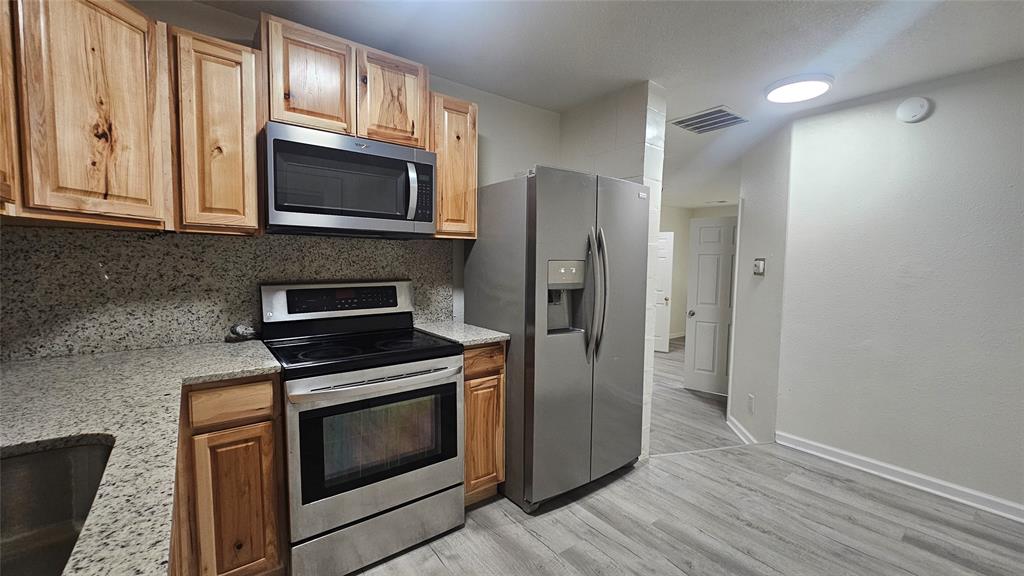 1015 South Welch Street, Unit A Denton, TX 76201 - Photo 15 of 21 a kitchen with stainless steel appliances granite countertop a stove a microwave and a refrigerator