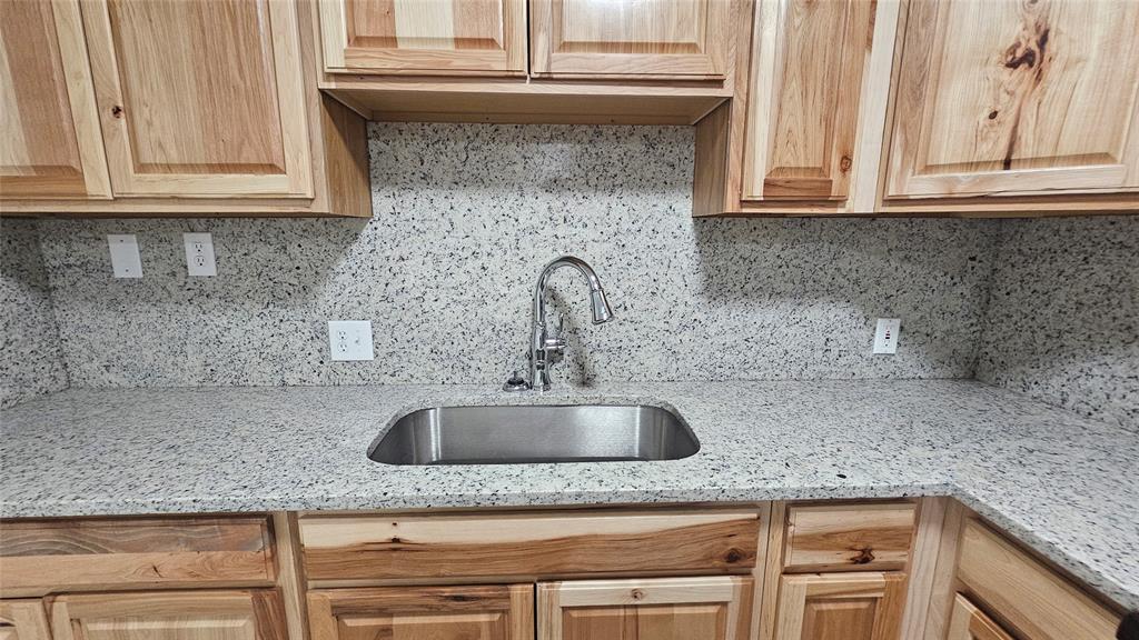 1015 South Welch Street, Unit A Denton, TX 76201 - Photo 16 of 21 a kitchen with granite countertop a sink and cabinets