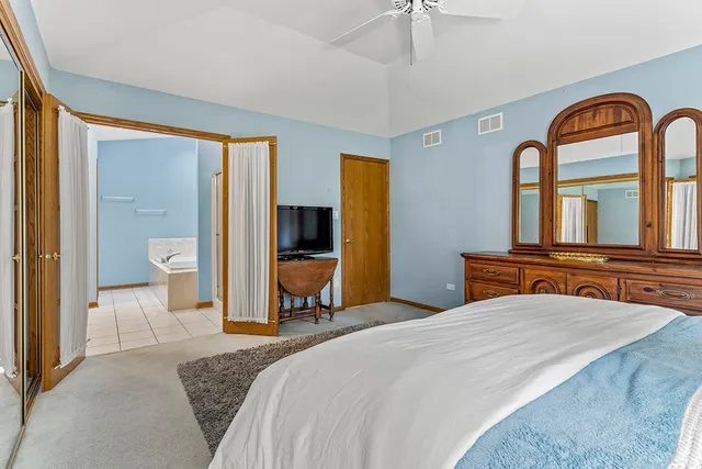 a bedroom with a bed and a large mirror on the dresser
