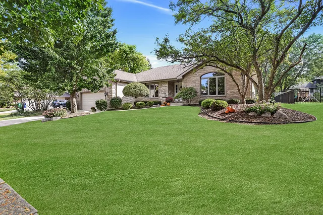 a front view of a house with a garden and trees