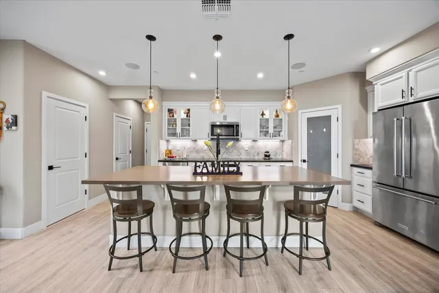 a kitchen with stainless steel appliances a dining table chairs refrigerator sink and cabinets