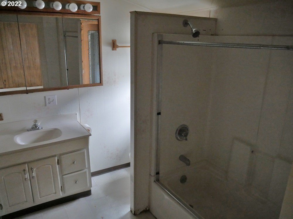 628 Southwest 4th Street Pendleton, OR 97801 - Photo 13 of 15 a bathroom with a granite countertop sink a mirror and a shower