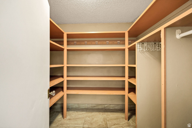 1365 Sumac Drive Logan, UT 84321 - Photo 22 of 66 Walk-in closet featuring extensive built-in shelving, a hanging rod, light-colored walls, and tiled flooring