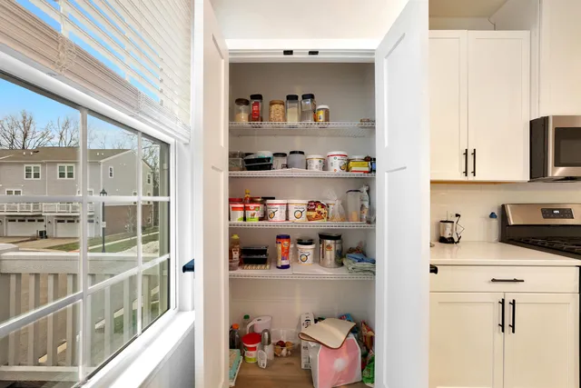 a kitchen with stainless steel appliances a lot of white cabinets and a wooden floor