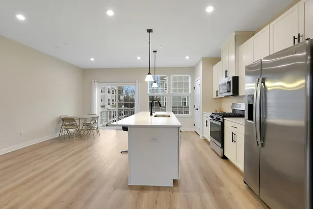 a large white kitchen with a refrigerator a stove a sink dishwasher a oven with white cabinets and wooden floor