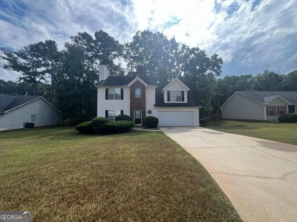a front view of a house with a garden and trees