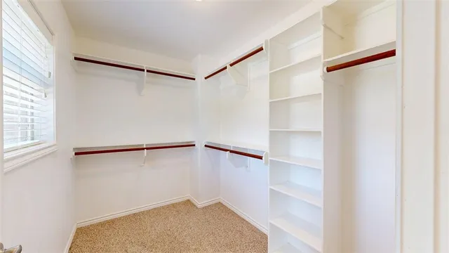 a view of an empty room and bathroom with a fan