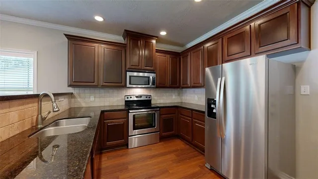 a kitchen with stainless steel appliances granite countertop sink stove top oven and refrigerator