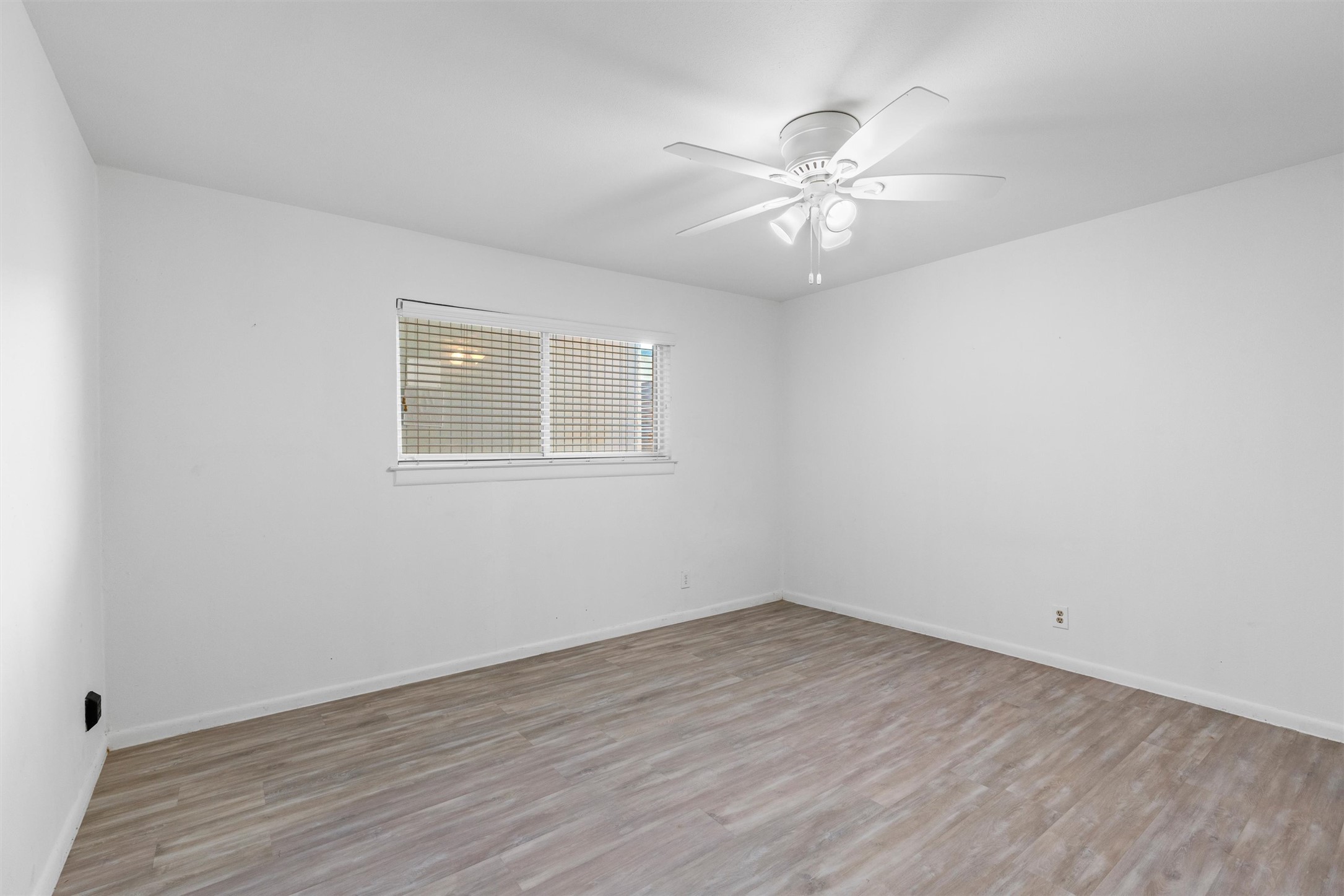 2208 Enfield Road, Unit 10500 Austin, TX 78703 - Photo 19 of 34 Bright room featuring light wood-finish flooring, white walls, and a ceiling fan with integrated lighting