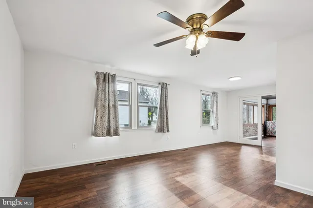 a view of an empty room with window and wooden floor