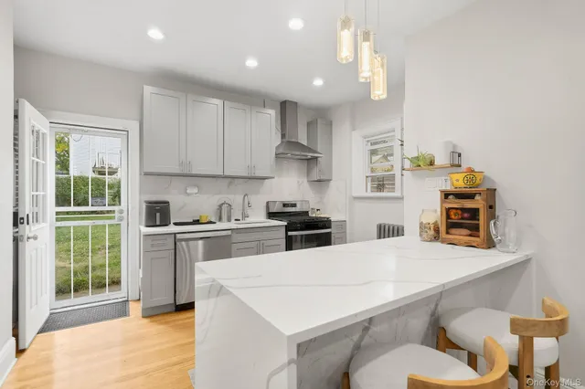 a kitchen with stainless steel appliances a stove a sink a kitchen island with a dining table and chairs