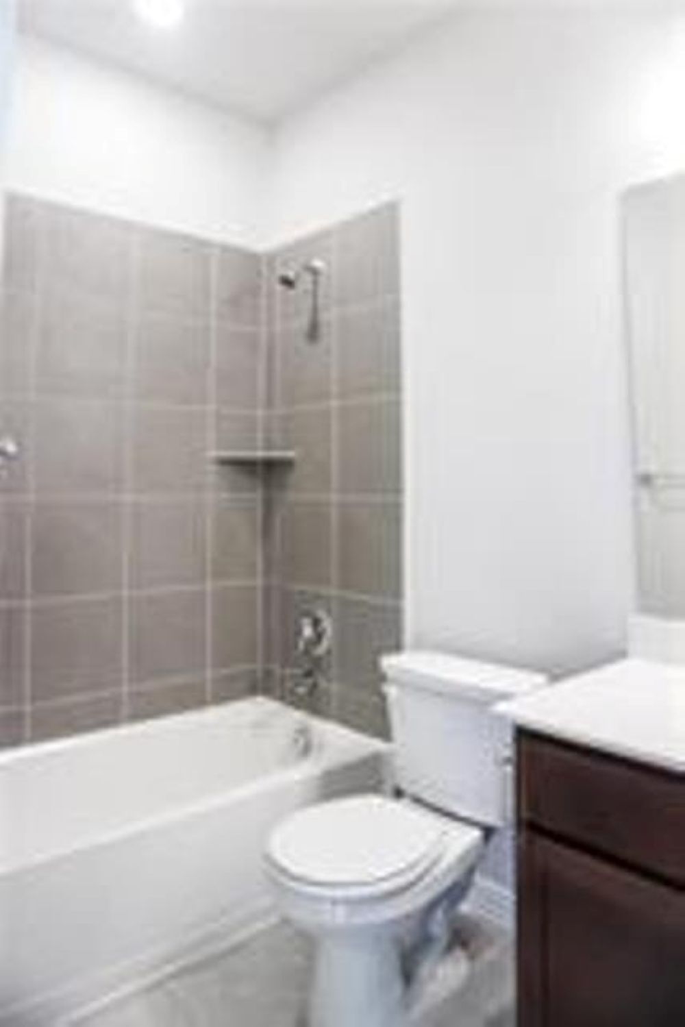 4021 Gildas Path Pflugerville, TX 78660 - Photo 17 of 19 Bathroom featuring a white tub, chrome shower fixtures, and gray wall tiles
