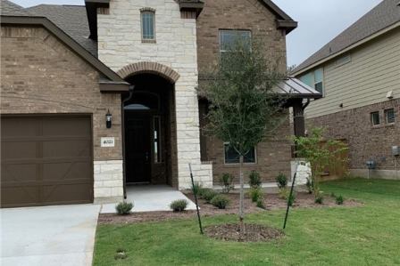 4021 Gildas Path Pflugerville, TX 78660 - Photo 2 of 19 Brick and stone facade featuring an arched entry, a covered porch, a two-car garage, and established landscaping