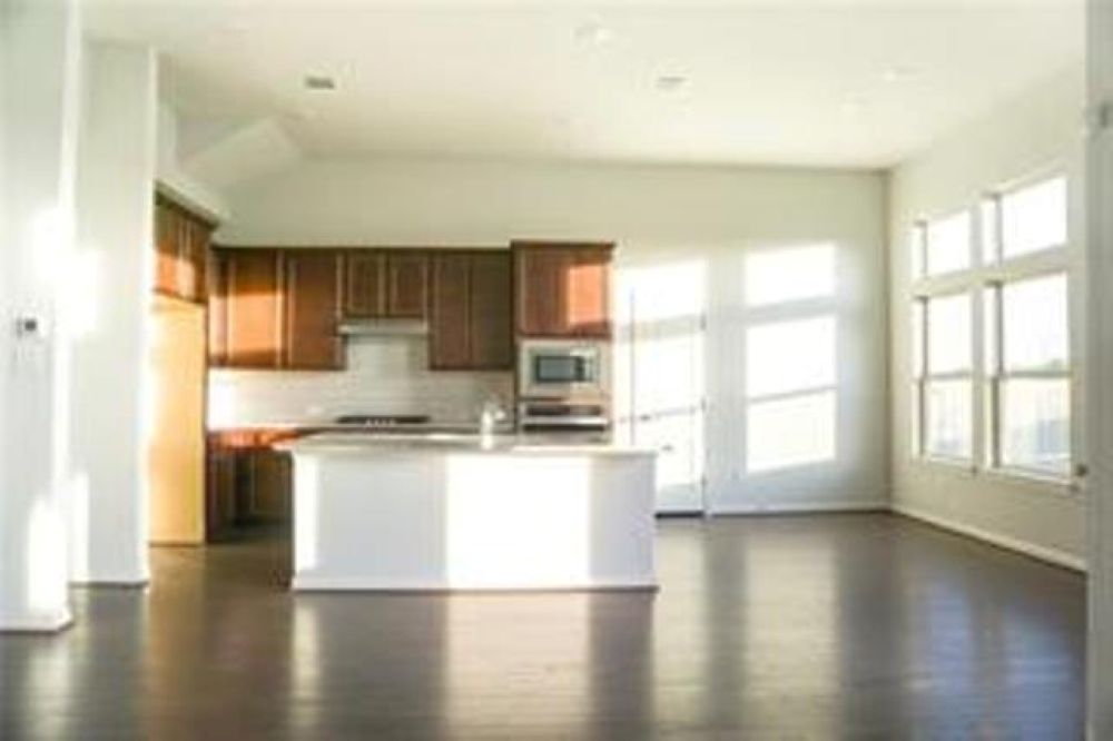 4021 Gildas Path Pflugerville, TX 78660 - Photo 6 of 19 Open-concept kitchen and living area featuring dark wood-finish flooring, a central island, and abundant natural light from large windows