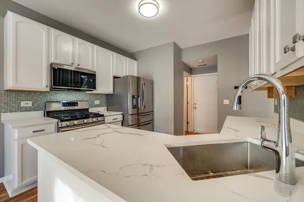 a kitchen with stainless steel appliances a stove a sink a refrigerator white cabinets and a refrigerator