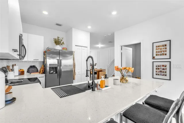 a kitchen with stainless steel appliances granite countertop a refrigerator and a sink