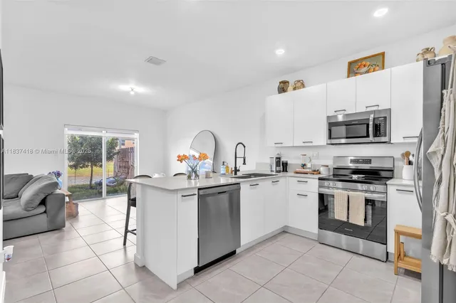 a kitchen with stainless steel appliances a stove a sink a microwave and a refrigerator