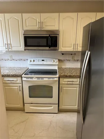 a kitchen with granite countertop white cabinets and stainless steel appliances