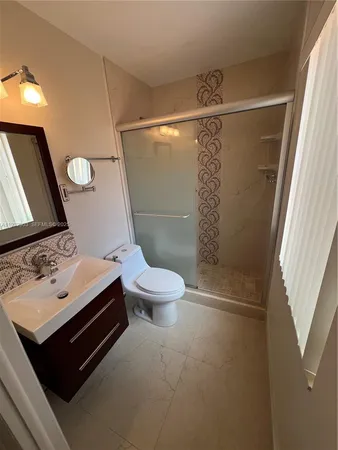 a bathroom with a sink a toilet a mirror and shower