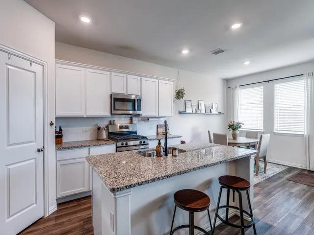 a kitchen with granite countertop kitchen island white cabinets and stainless steel appliances