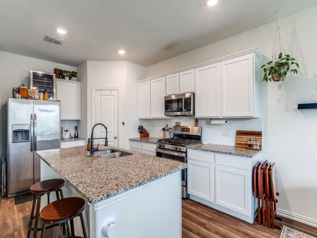 a kitchen with granite countertop a stove top oven a sink dishwasher and microwave with wooden floor