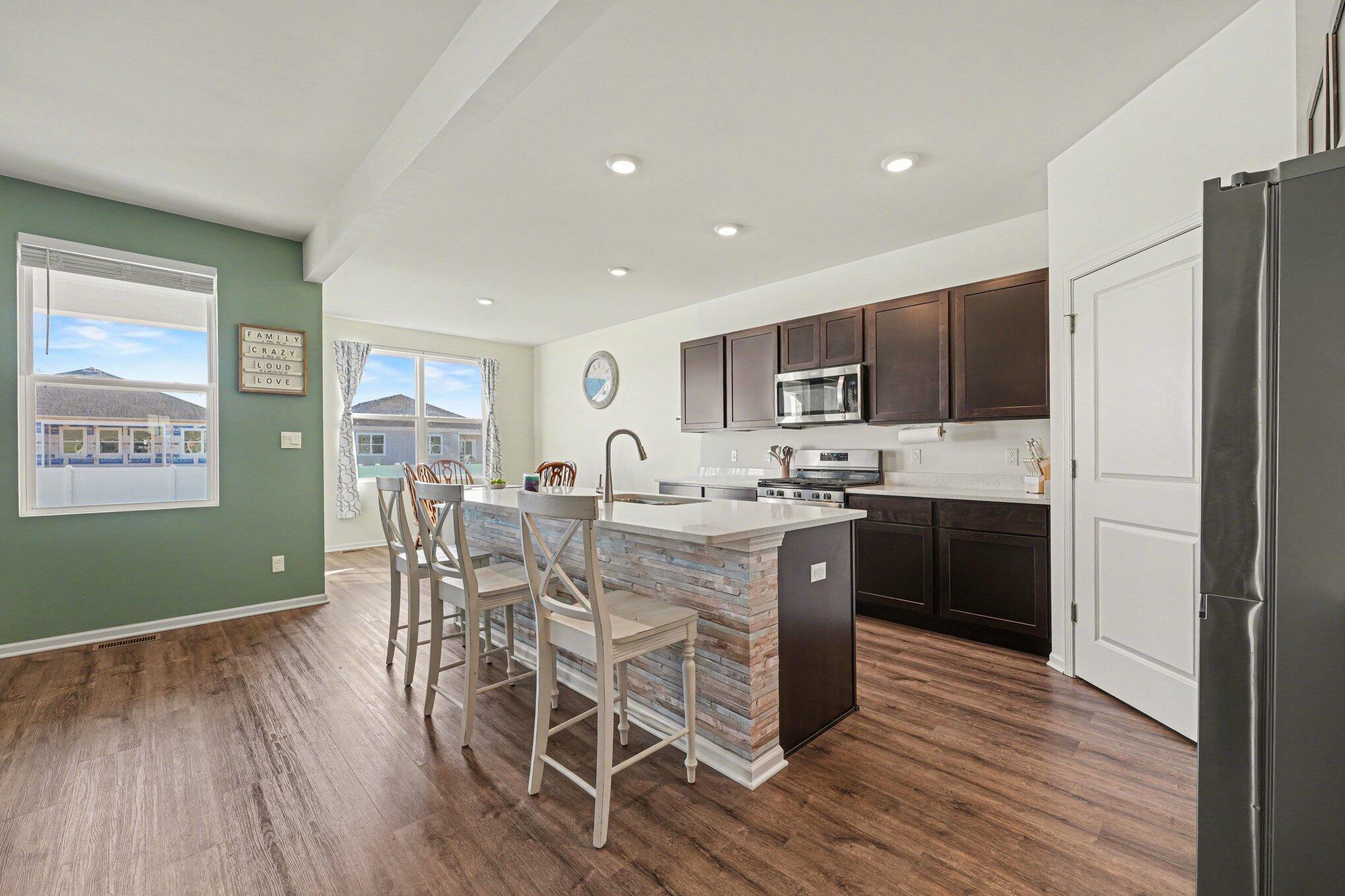 7787 West 105th Place Crown Point, IN 46307 - Photo 9 of 32 a kitchen with stainless steel appliances granite countertop a refrigerator a stove top oven a sink dishwasher a dining table and chairs with wooden floor