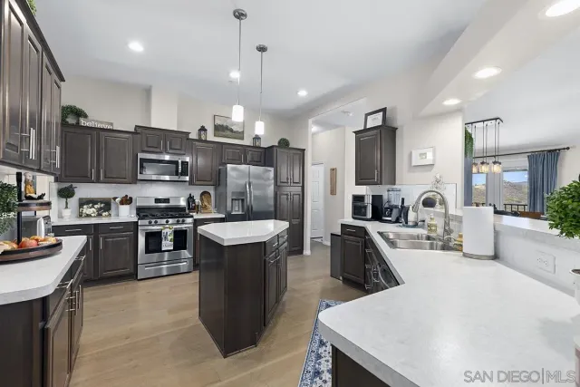 a kitchen with stainless steel appliances granite countertop a refrigerator a sink dishwasher a stove top oven a refrigerator with wooden cabinets and floor