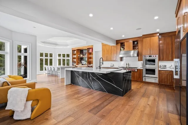 a living room with stainless steel appliances granite countertop a sink dishwasher and a flat screen tv
